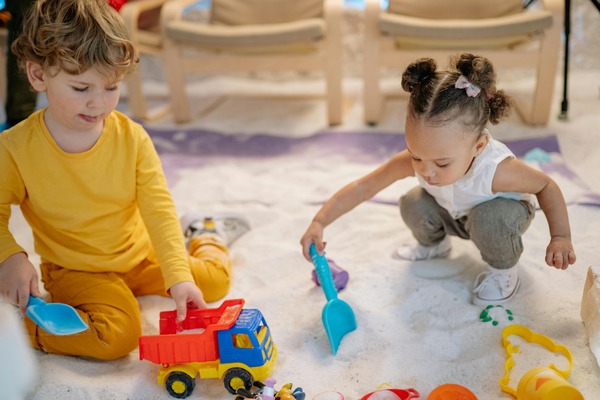 Group of toddlers collaboratively playing with colorful building blocks, developing fine motor skills and creativity at Quokka Kids